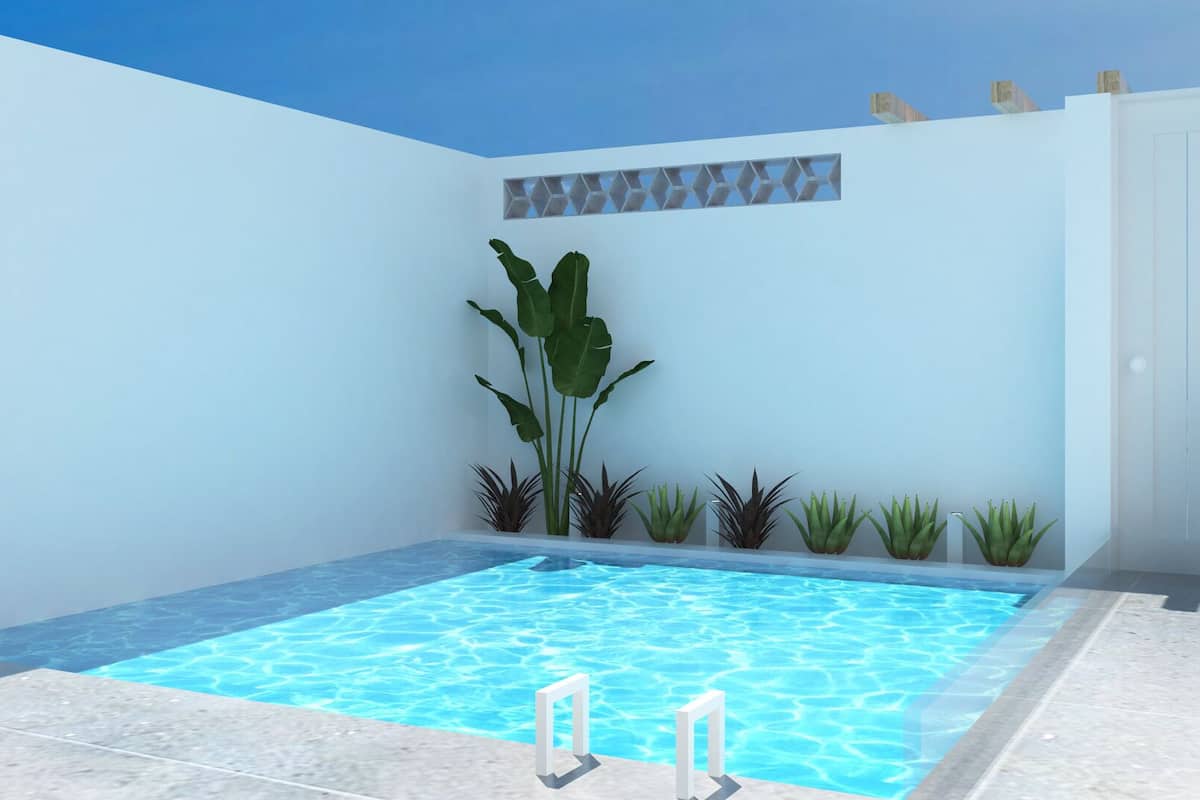 A modern indoor swimming pool with a clear blue water surface, surrounded by a white wall with a geometric pattern.