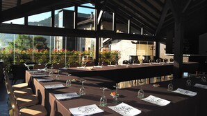 An outdoor dining area with tables set for a meal, surrounded by large windows and a view of the countryside. - Izalde (Ayala)