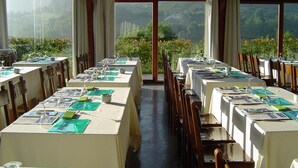 A restaurant with tables set for dining, large windows offering a view of the mountains. - Izalde (Ayala)