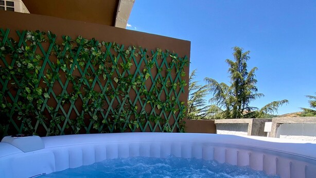 Un jacuzzi con superficie de agua azul cristalina, rodeado por un borde de piscina blanco.