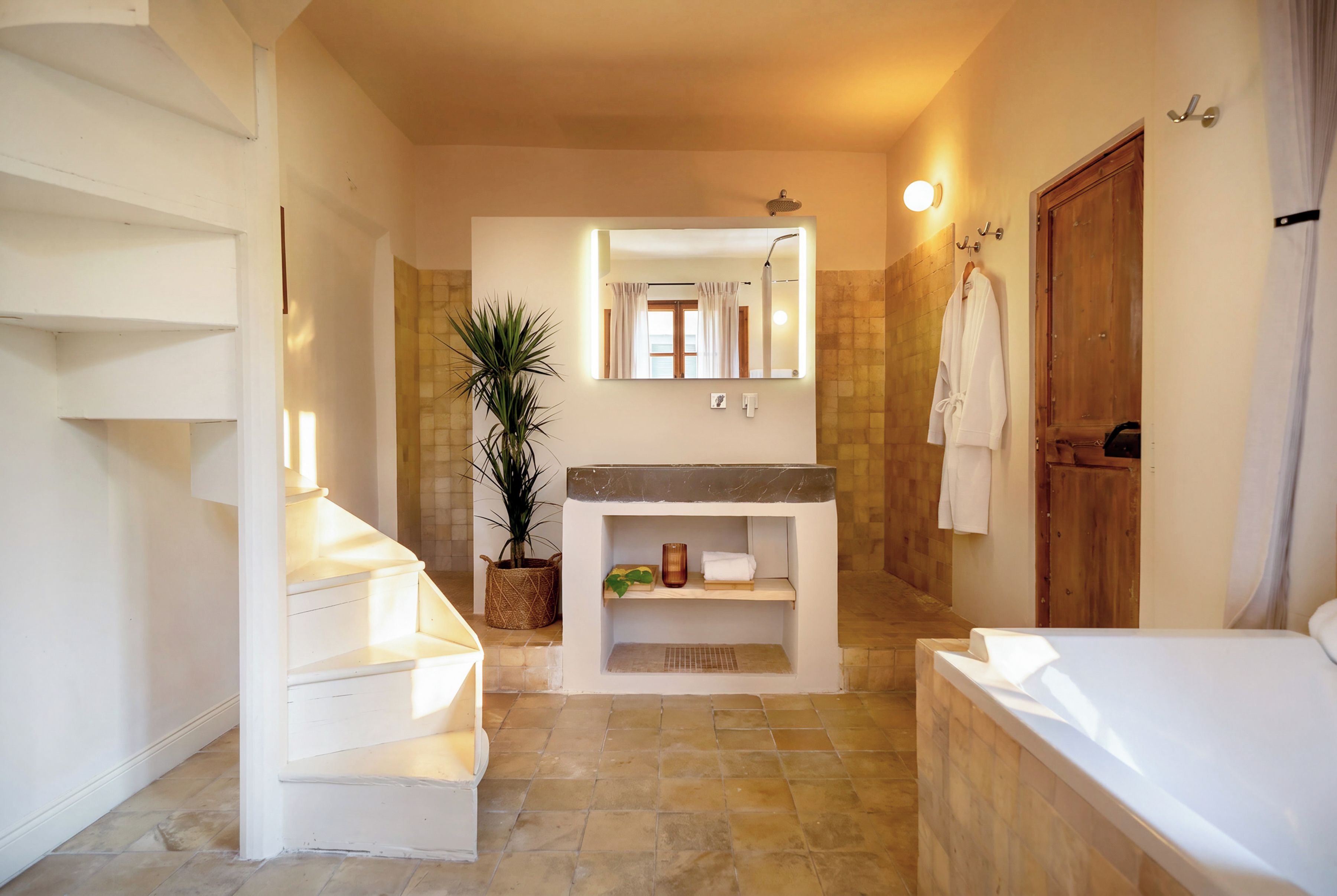 A bathroom with a white sink, a mirror, a shower, and a wooden door.
