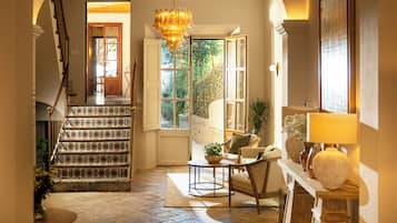 Una escalera con baldosas estampadas que conduce a una habitación con un candelabro, un sofá y una mesa.