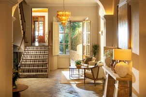 A staircase with patterned tiles leading to a room with a chandelier, a sofa, and a table.