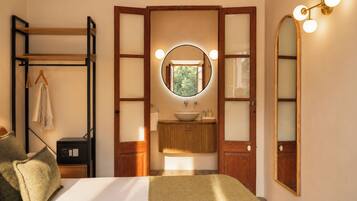 Une chambre à coucher avec un lit, une armoire, un miroir, un lavabo et une fenêtre.