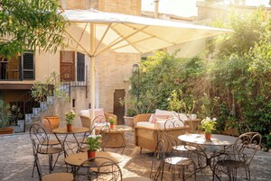 Un patio al aire libre con mobiliario de mimbre, una mesa y un gran paraguas.
