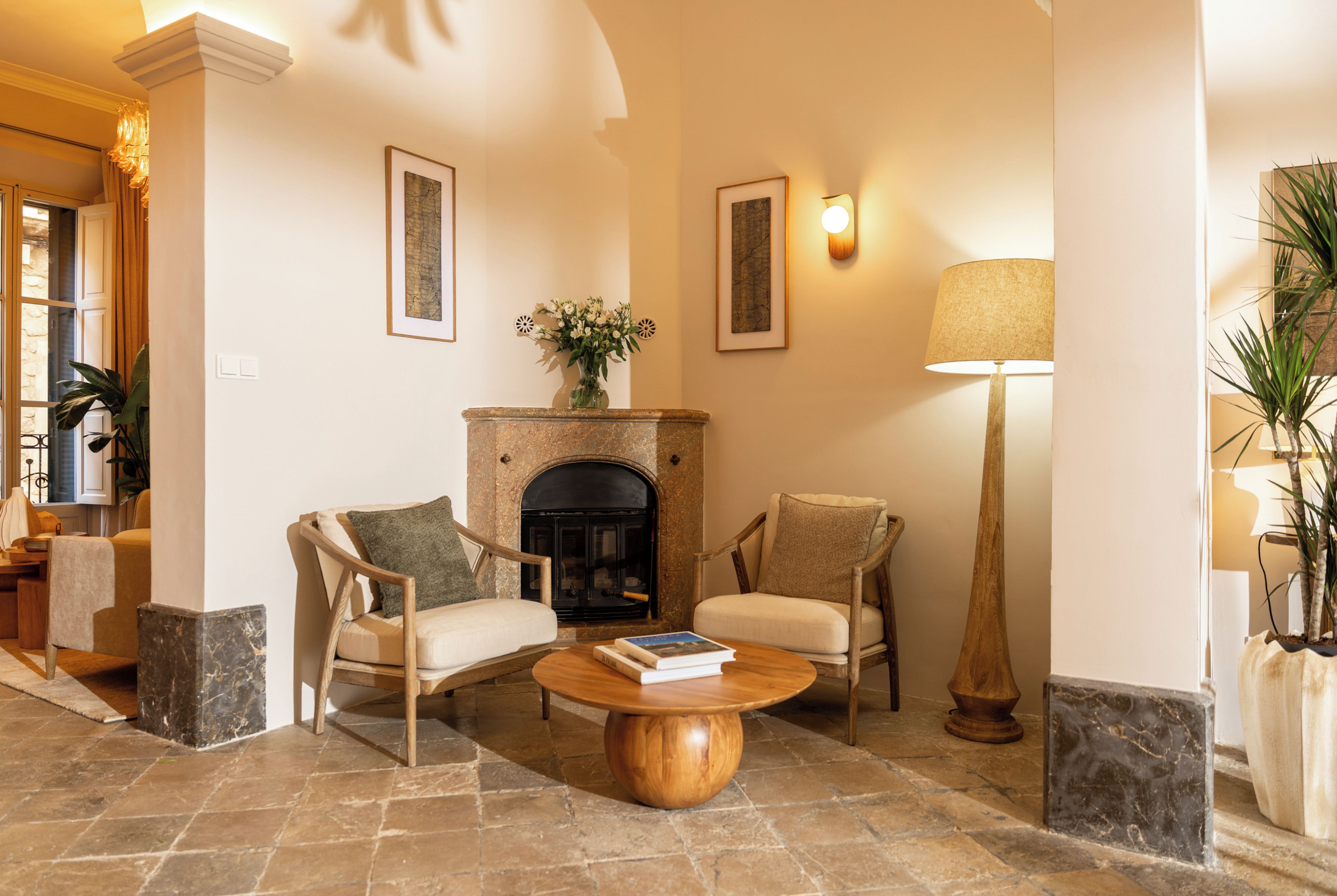 A cozy living room with a fireplace, two armchairs, a coffee table, and a floor lamp.
