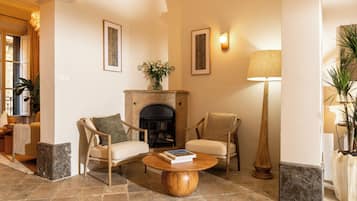 A cozy living room with a fireplace, two armchairs, a coffee table, and a floor lamp.