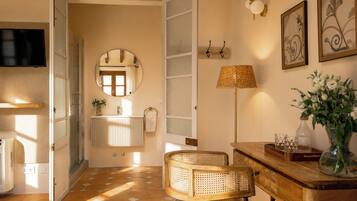 Une salle de bain avec un miroir rond, un porte-serviettes, un radiateur et un espace douche.