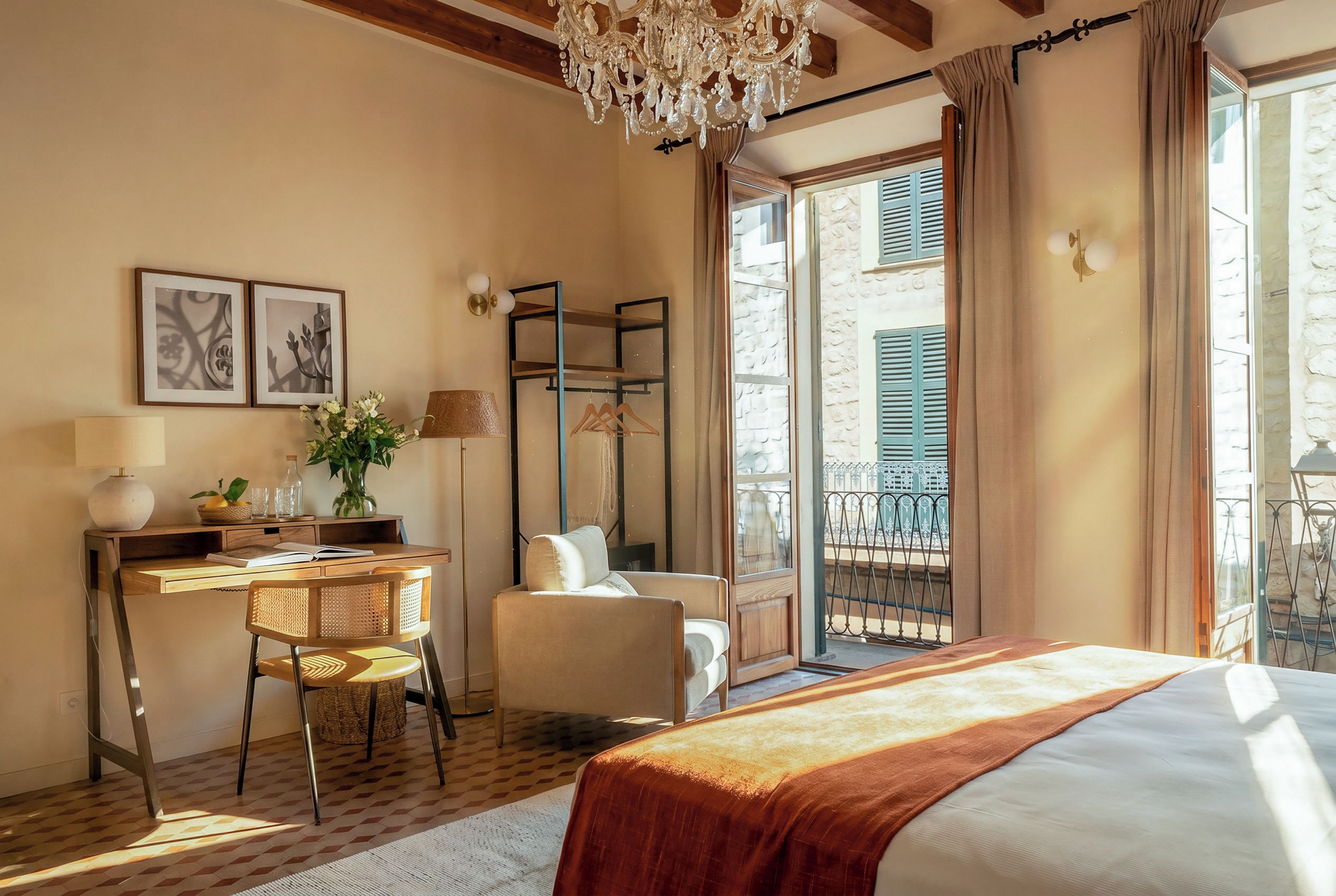 Habitación de hotel con cama, escritorio con silla, planta colgante y vista al exterior.