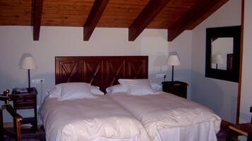 Ein Doppelbett mit Holz-Kopfteil, zwei Nachttische mit Lampen und ein Spiegel an der Wand.