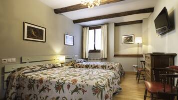 A bedroom with two beds, a dresser, a TV, and a window with curtains.