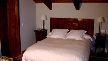Ein Hotelzimmer mit einem großen Bett, einem Holz-Kopfbrett, zwei Nachttischen mit Lampen und einem kleinen Sessel.