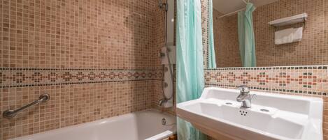 A bathroom with a bathtub, a sink, and a shower area.