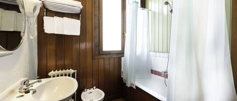 A bathroom with a sink, bidet, and bathtub.