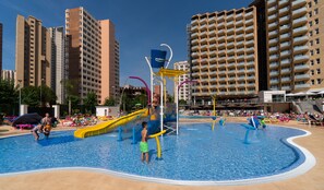 Una piscina al aire libre, sombrillas, sillones reclinables de piscina