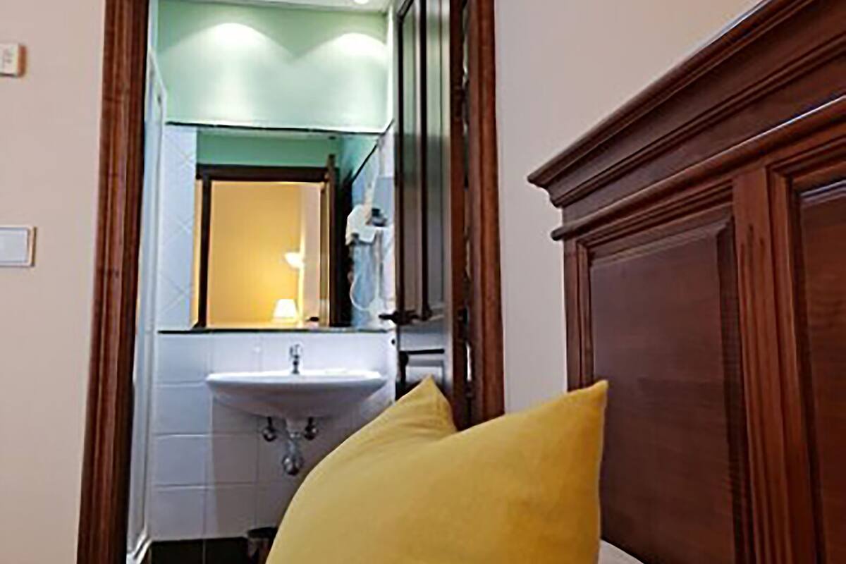 A narrow hallway leading to a bathroom with a sink and mirror.
