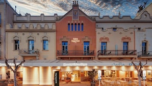 Fachada de hotel con balcones, un reloj central y un letrero que dice "Sercotel Kalma Sitges".