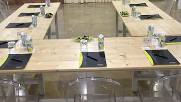Un salón de conferencias con largas mesas, cada una con botellas de agua, bolígrafos y blocs de notas.