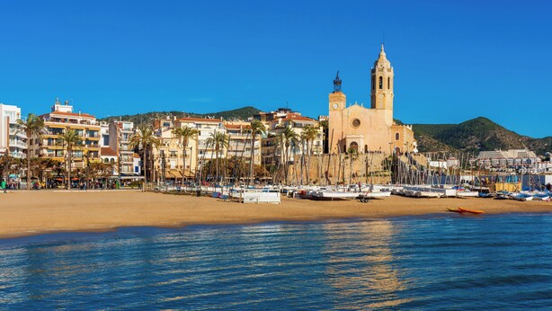 Un pueblo costero con una iglesia destacada, una playa y un puerto deportivo.