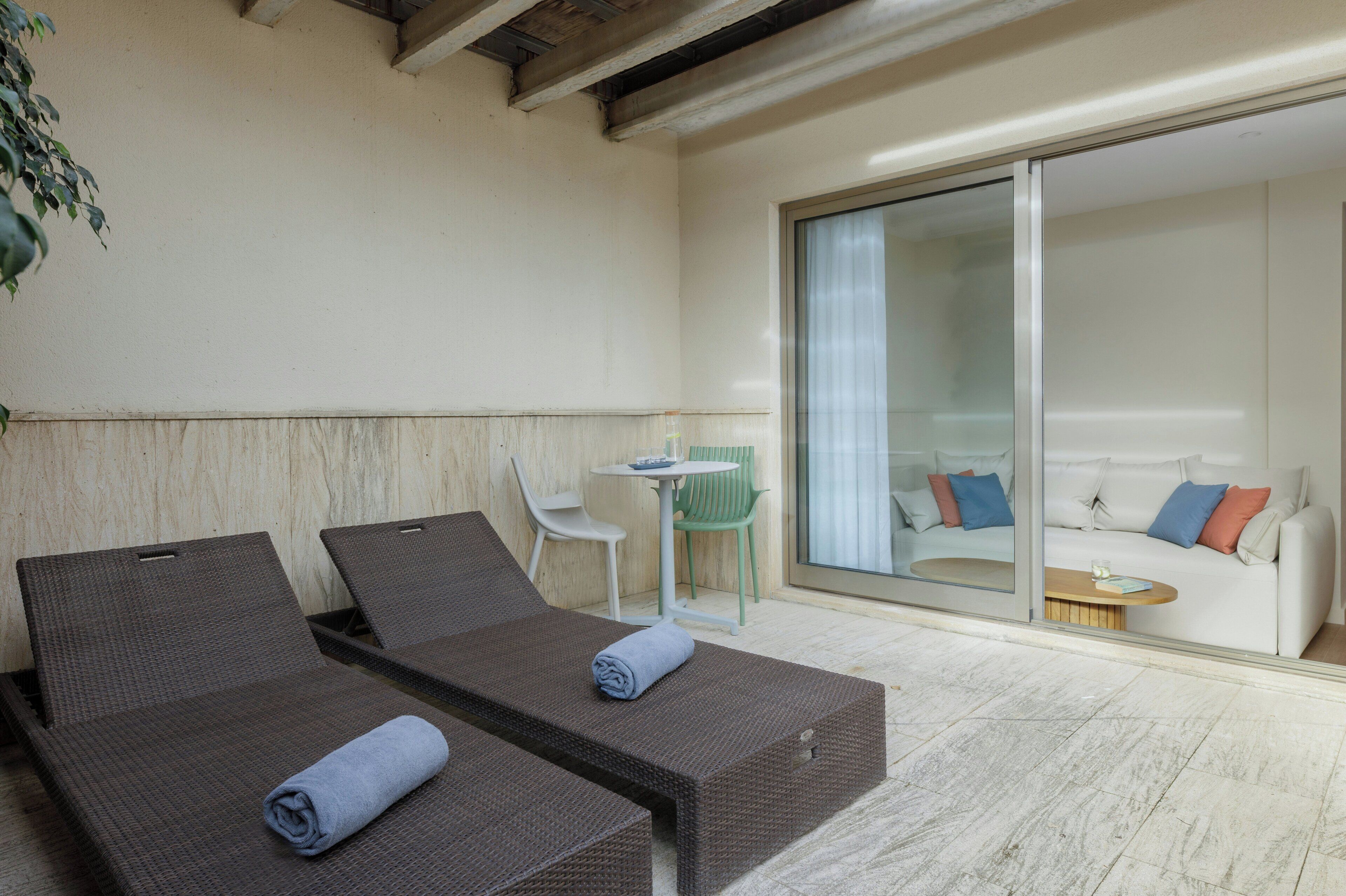 A room with two reclining chairs, a small table, and a sofa with pillows.