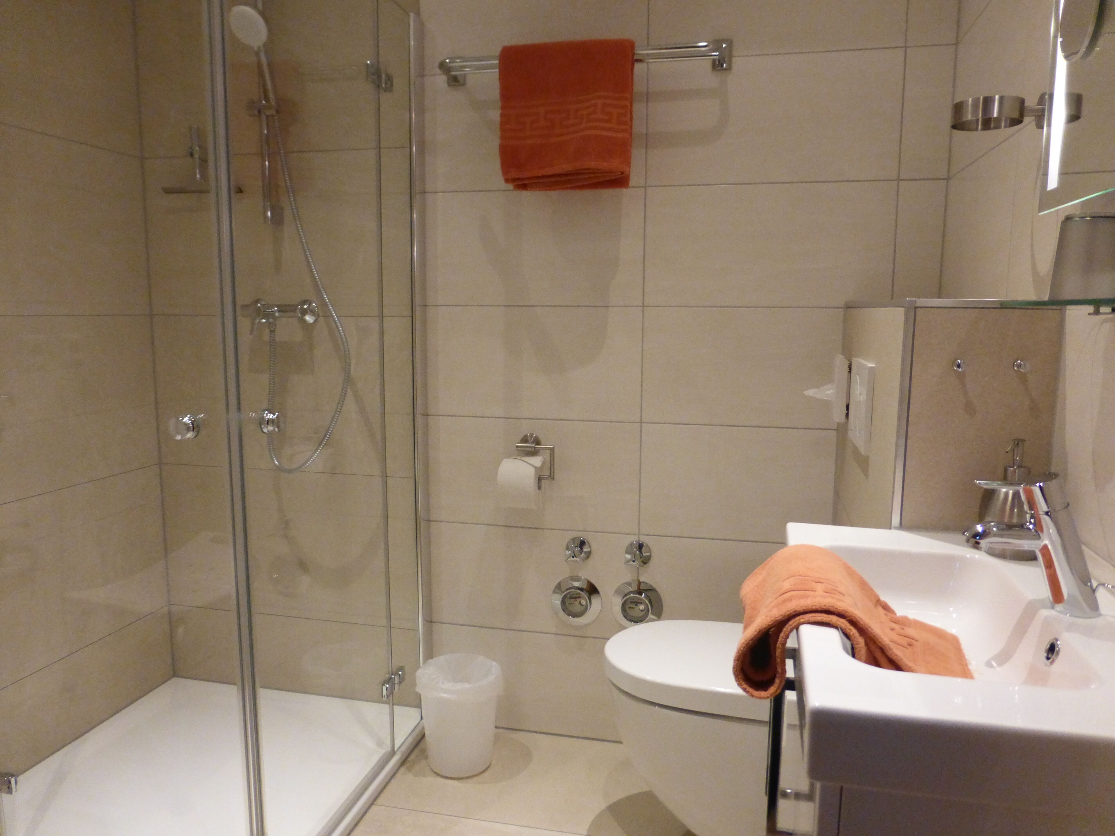 A modern bathroom with a glass-enclosed shower, a white toilet, and a sink with a towel.