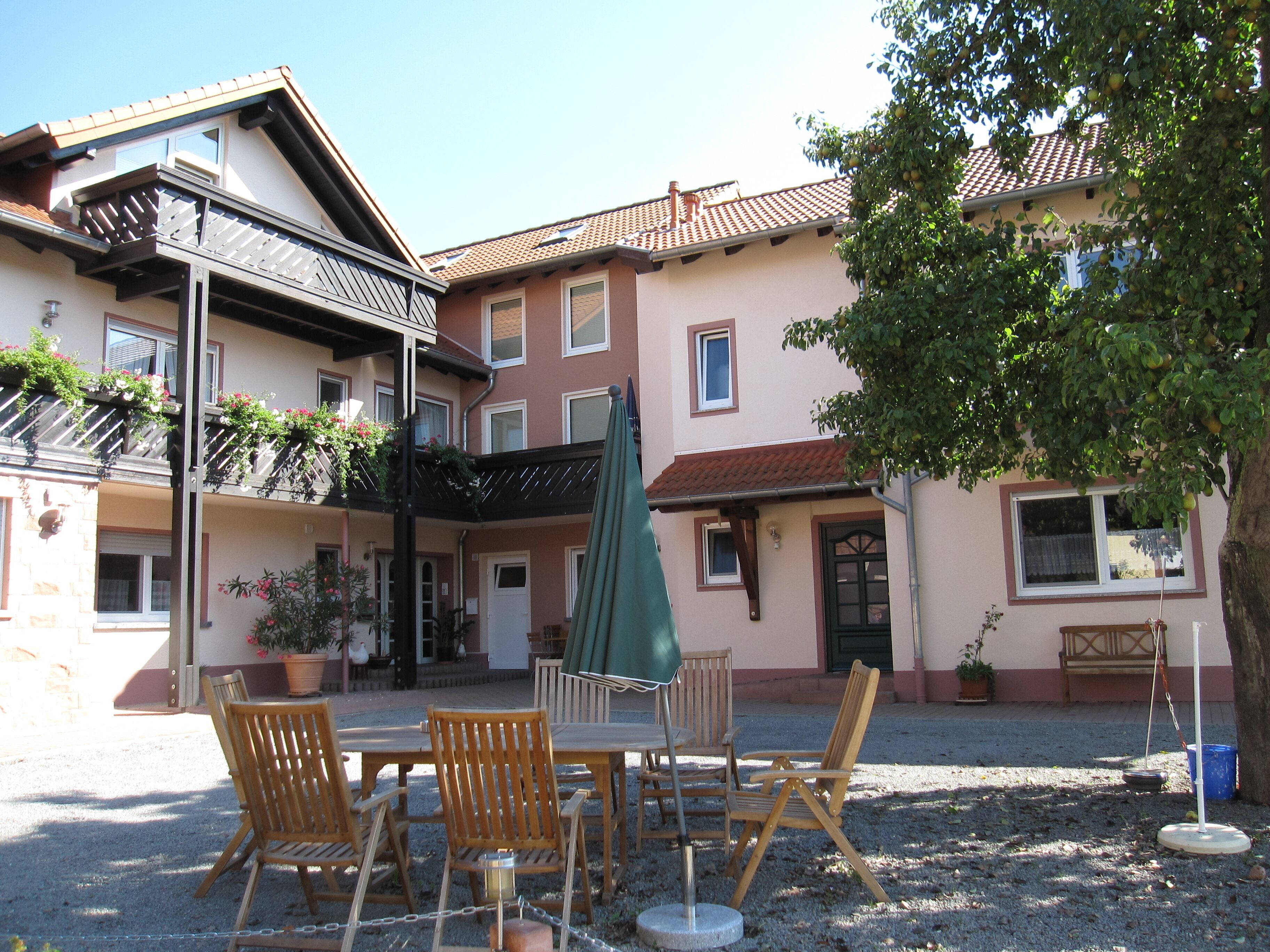 A courtyard with a table and chairs, surrounded by buildings with balconies and potted plants.