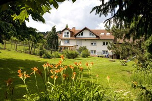 Ein zweistöckiges Haus mit gepflegtem Rasen und einer Hängematte im Garten.