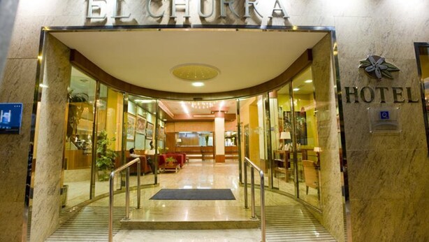 The entrance to the El Chorro Hotel with a glass facade, a reception area, and a staircase leading inside. - Hotel El Churra (Murcia)