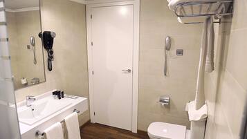 A bathroom with a sink, toilet, and a mirror.