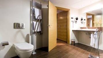 Un baño moderno con inodoro, toallero, ducha y tocador con espejo.