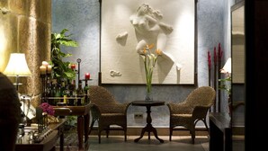 A bar area with wicker chairs, a small table with a vase of flowers, and a large wall-mounted artwork. - Hotel El Churra (Murcia)