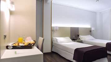 Een hotelkamer met twee bedden, een bureau met ontbijt en een spiegel boven het bed.