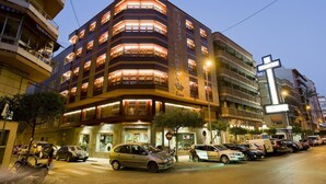 A multi-story hotel with illuminated balconies and a prominent cross sign. - Hotel El Churra (Murcia)