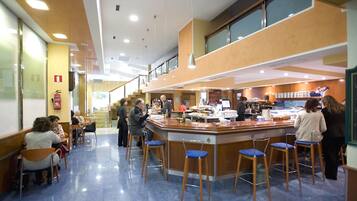 Een modern interieur met een centrale bar, zitgedeeltes en een trap naar een hoger gelegen niveau.
