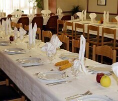 Un comedor con mesas dispuestas para el servicio, sillas y un frutero en la mesa.