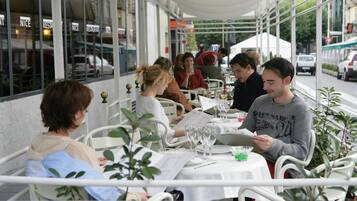 Een café met terras, witte metalen stoelen en tafels met menukaarten en drankjes.