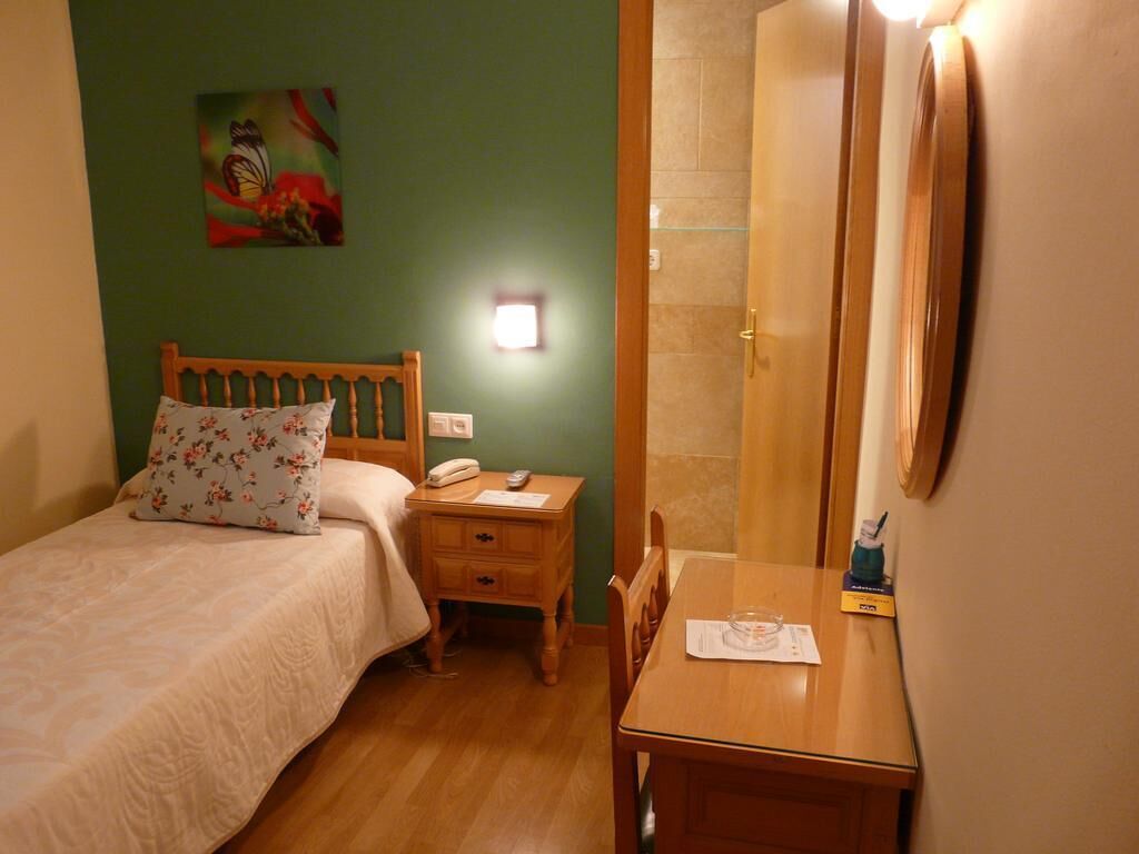 A bedroom with a bed, bedside table, and a mirror.