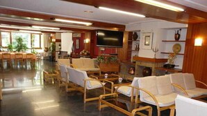A spacious lobby with wooden furniture, a flat-screen TV, and a fireplace. - Nice (La Seu d'Urgell)