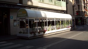 A restaurant with a covered outdoor seating area, a visible entrance, and a sign indicating it is a restaurant.
