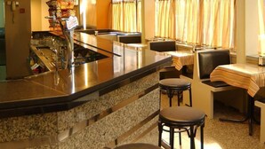 A bar area with granite countertops, bar stools, and a wine rack with bottles. - Nice (La Seu d'Urgell)