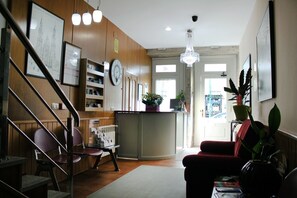 A hotel lobby with a reception desk, a clock, a chandelier, and a staircase. - Hotel Hórreo by Bossh! Hotels (Santiago de Compostela)