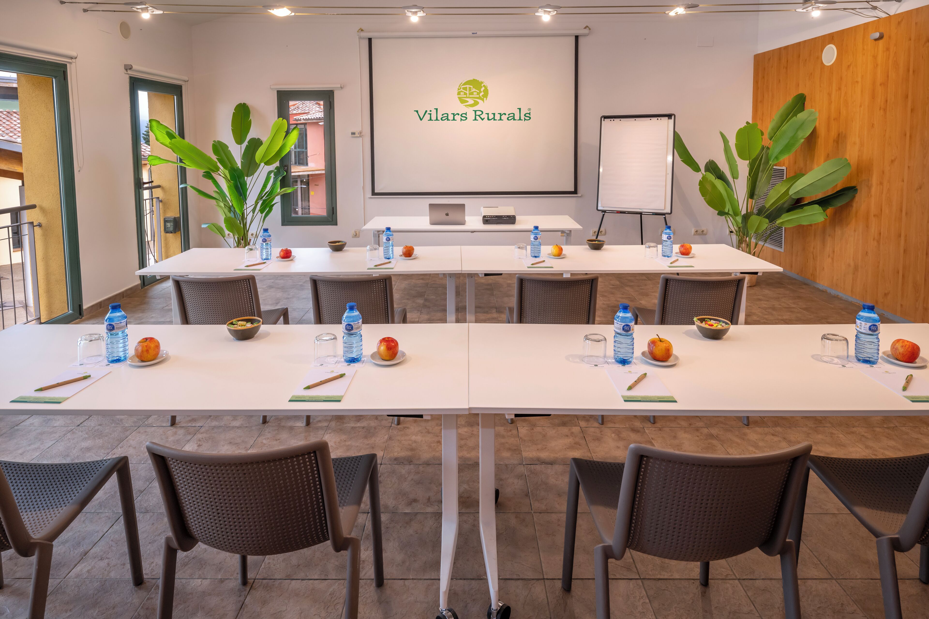 A conference room with a long table, chairs, a projector screen, and a whiteboard.