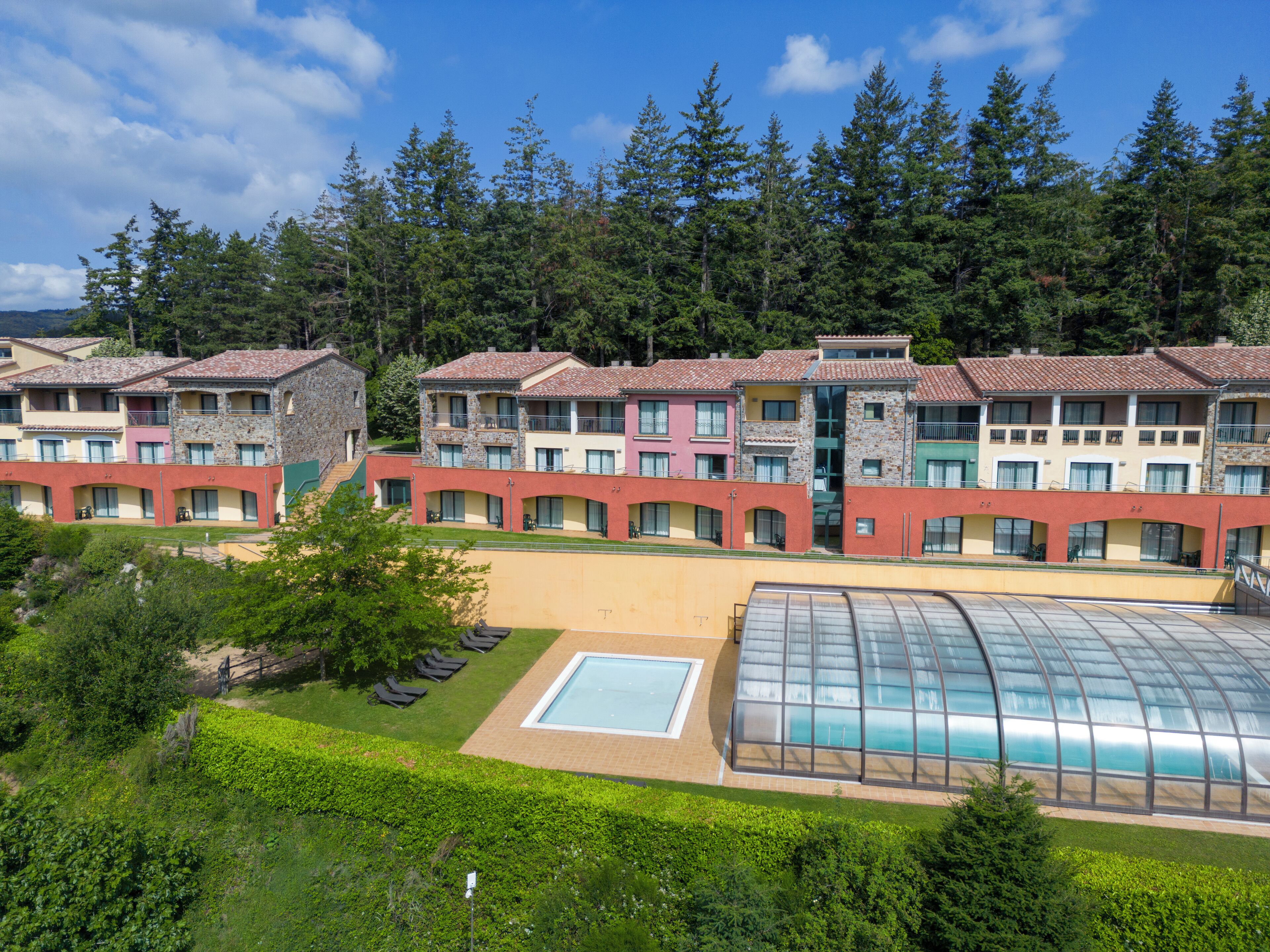 A hotel with multiple buildings, a swimming pool, and a greenhouse.