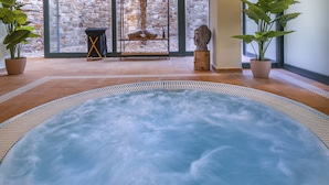 A hot tub area with a stone wall and potted plants. - Vilar Rural de Sant Hilari by Serhs Hotels (Sant Hilari Sacalm)