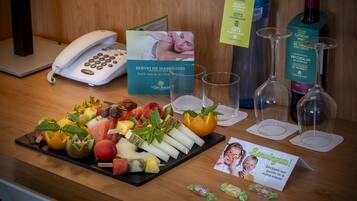 Una recepción con una bandeja de frutas, copas de vino, un teléfono y tarjetas informativas.