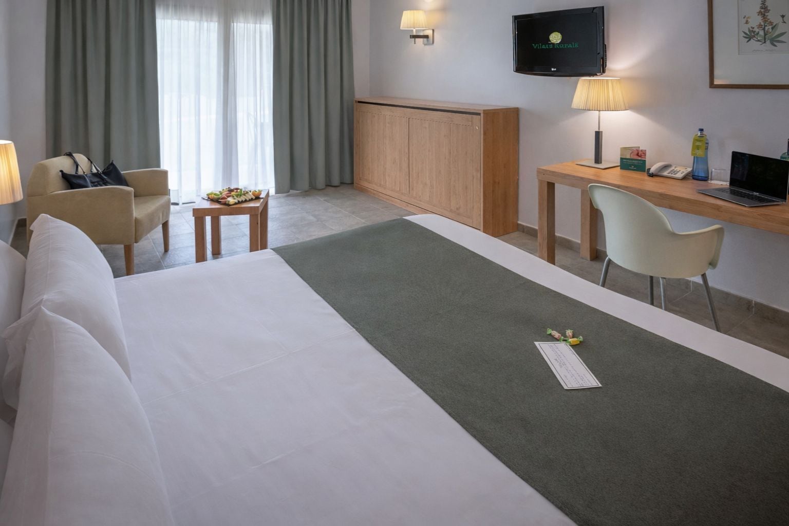 A hotel room with a bed, a desk, a chair, a television, and a window with curtains.
