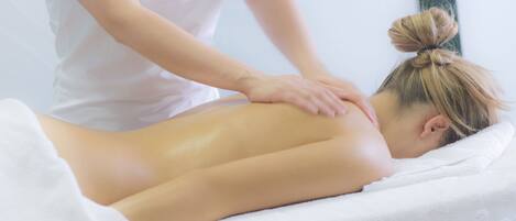 A person receiving a back massage on a massage table with a towel covering their lower body.