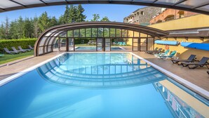 A swimming pool with a glass enclosure and lounge chairs. - Vilar Rural de Sant Hilari by Serhs Hotels (Sant Hilari Sacalm)