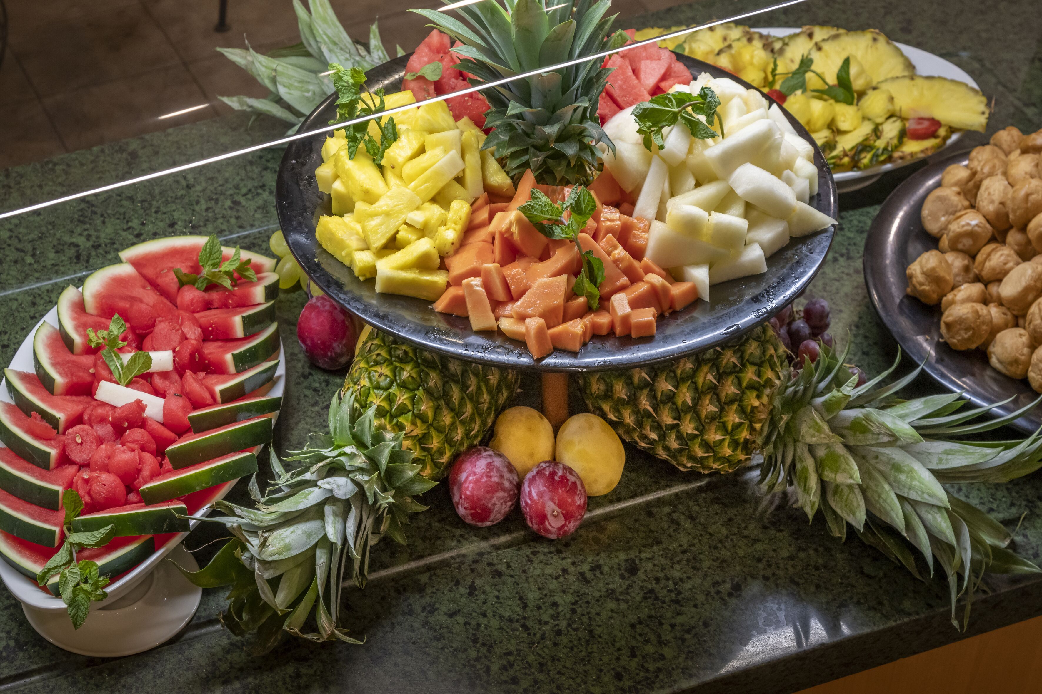 A buffet with various fruits and vegetables, including watermelon, pineapple, mango, and carrots.