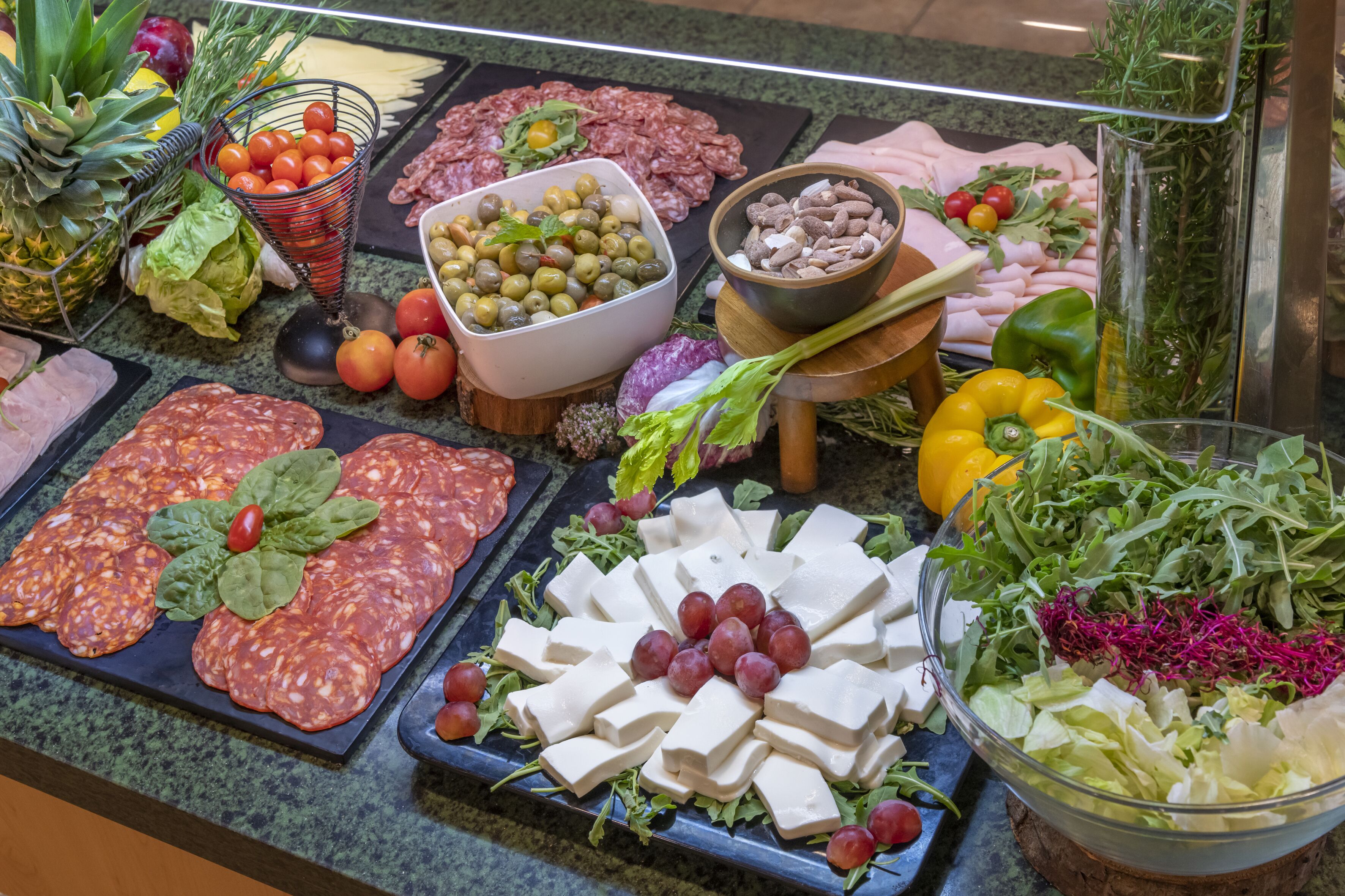 A variety of food items including meats, cheeses, olives, and vegetables displayed on a counter.